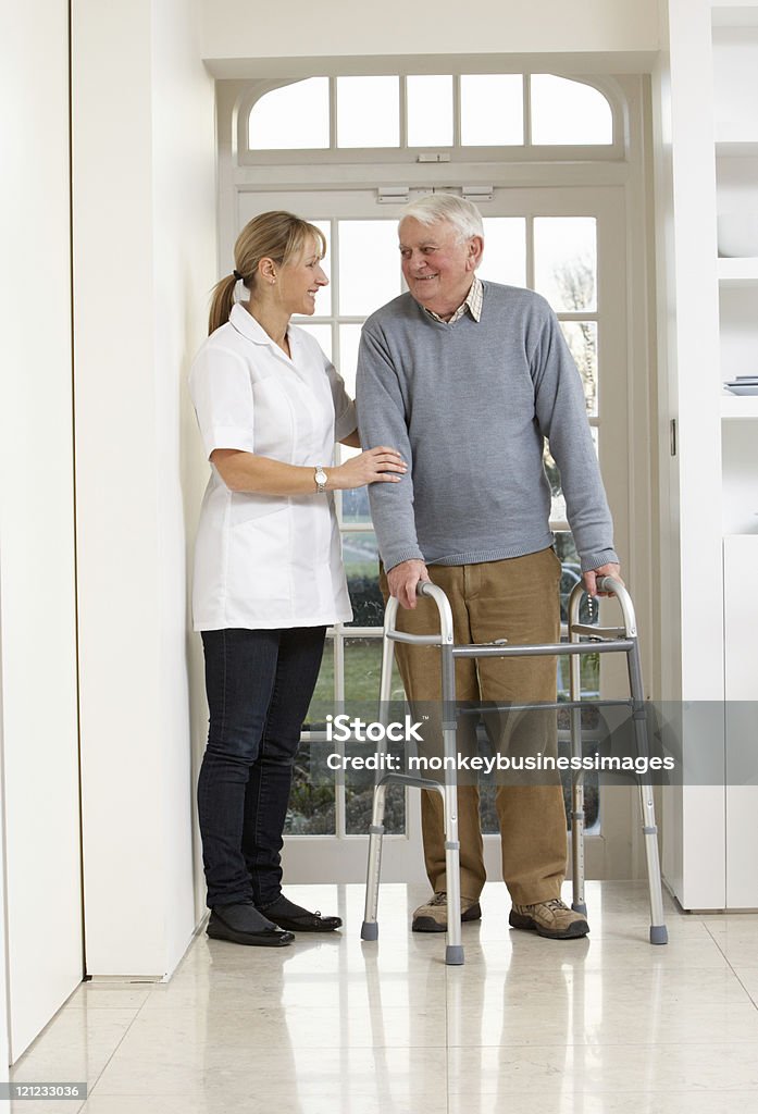 Cuidador ajudando sênior Homem idoso usando uma caminhada de quadro - Foto de stock de 60 Anos royalty-free