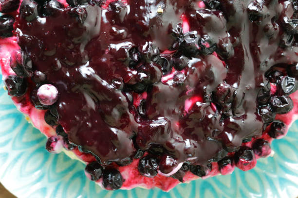 istock Image of blackcurrant cheesecake with buttery biscuit base on patterned blue plate, vanilla mascarpone cream cheese dessert pudding topped with cherry jam coulis and fresh blackcurrants, elevated view 1212331669