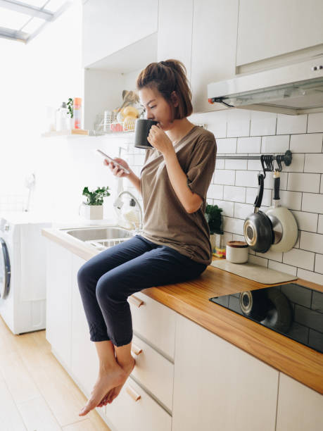 istock Young woman sitting in cozy kitchen and working on her mobile. 1212332398