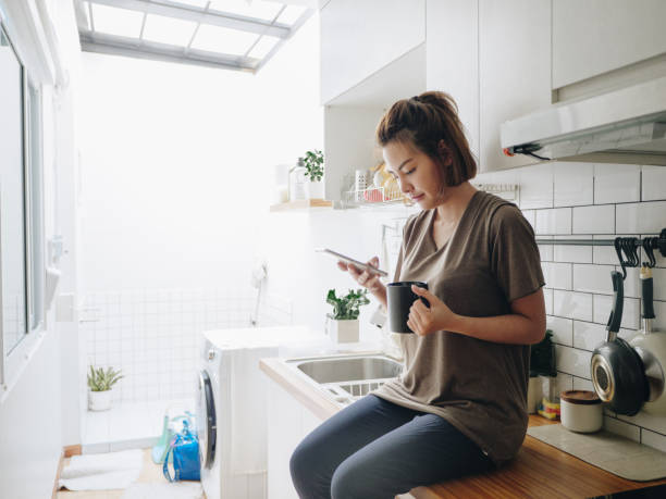 istock Young woman sitting in cozy kitchen and working on her mobile. 1212332538