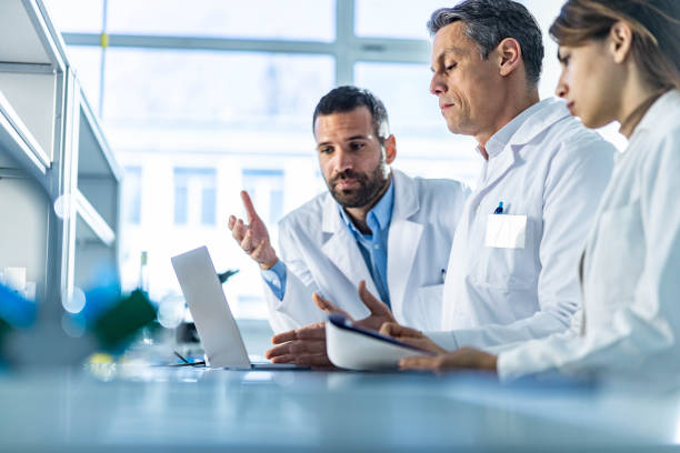 istock Team of scientists cooperating while working on laptop in laboratory. 1212332857