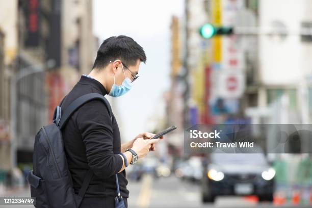 Un Chino Con Una Máscara Facial Está Leyendo Noticias En Su Teléfono Inteligente Mientras Espera Para Cruzar Una Calle En Taipei Taiwán Foto de stock y más banco de imágenes de Adulto