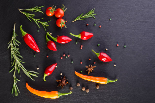 Different spices with tomato and  peppers on a black background