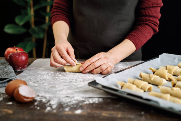 istock Women cooking cake in kitchen. She makes apple pie on dark background. 1212339566