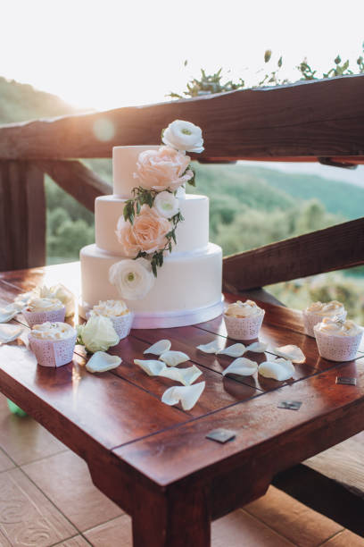 White wedding cake with flowers on a wooden table.