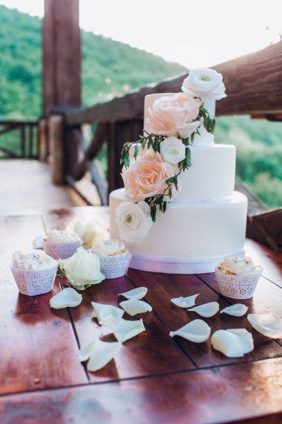 istock White wedding cake with flowers on a wooden table. 1212340902
