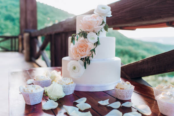 istock White wedding cake with flowers on a wooden table. 1212340937