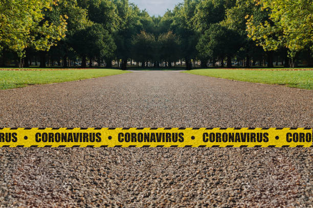 parks lockdown concept: an empty park bordered by a yellow and black safety tape with the word coronavirus after closing to prevent contagion spread. - bordered imagens e fotografias de stock