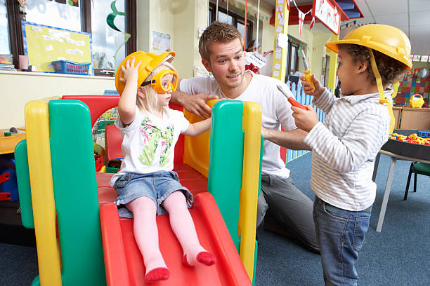 Man with nursery children playing together stock photo