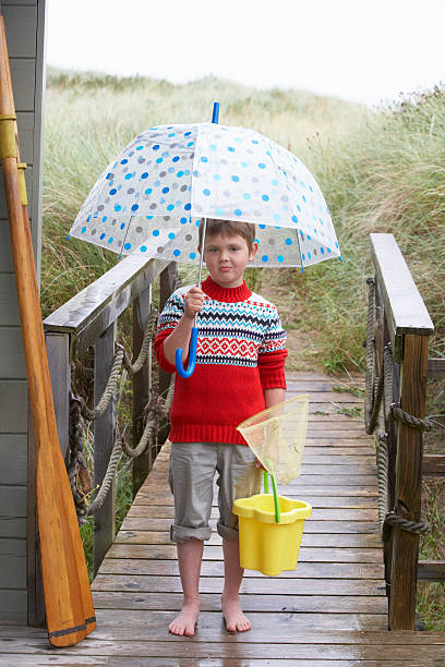 istock Boy standing on footbridge at beach with umbrella 121234390