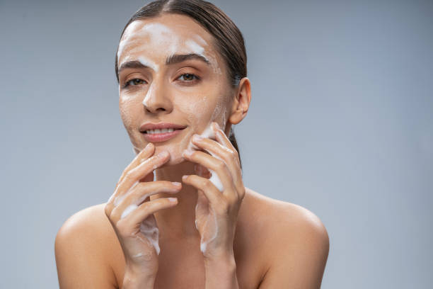 istock Smiling pretty woman washing her face with soap 1212344256