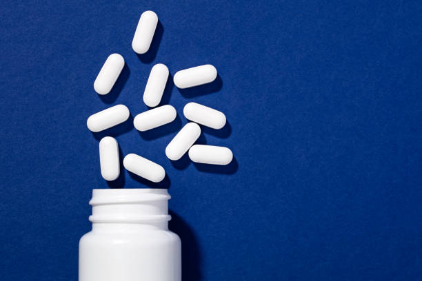istock White bottle and pills on blue background 1212346554
