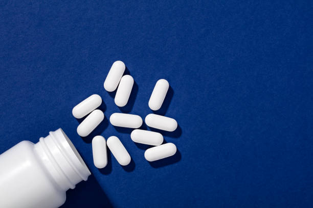 istock White bottle and pills on blue background 1212346588