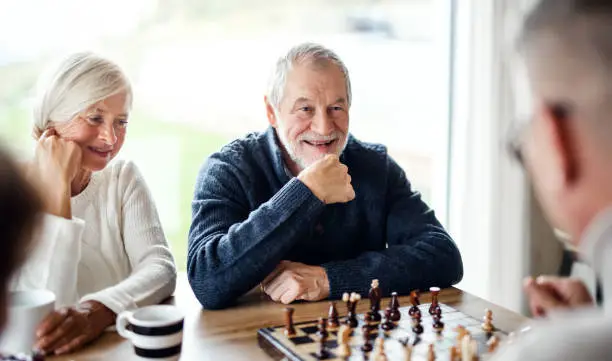 Group of happy senior friends at home, playing board games.