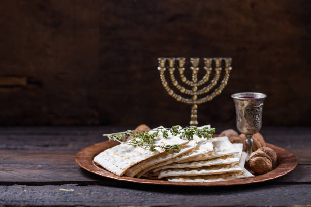 Passover, the Feast of Unleavened Bread, matzah bread and red wine glasses on the shinny round metal tray. stock photo