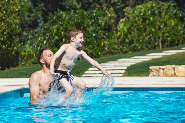istock Father and son jumping in pool 1212351972