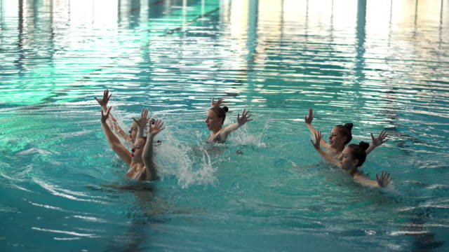 Synchronized swimming team doing a performance inside a public pool