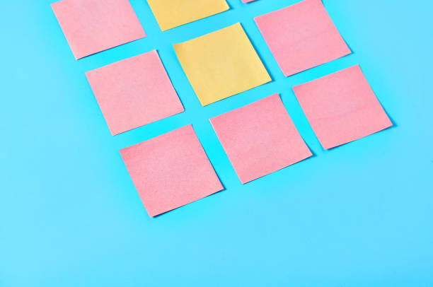 istock Two yellow and frame of pink square blank paper stickers on blue background. Copy space 1212357792