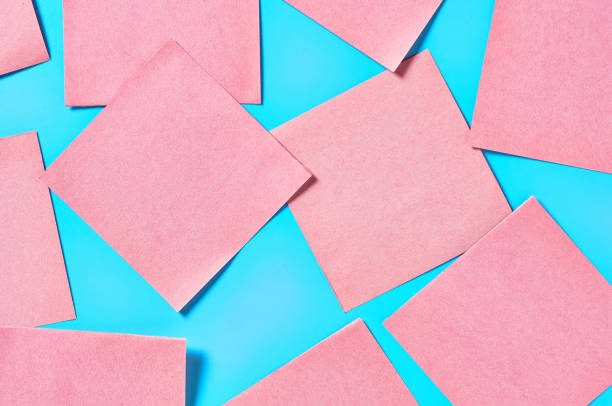 istock Scattered many pink square blank paper stickers on blue background. Copy space. Top view 1212357811