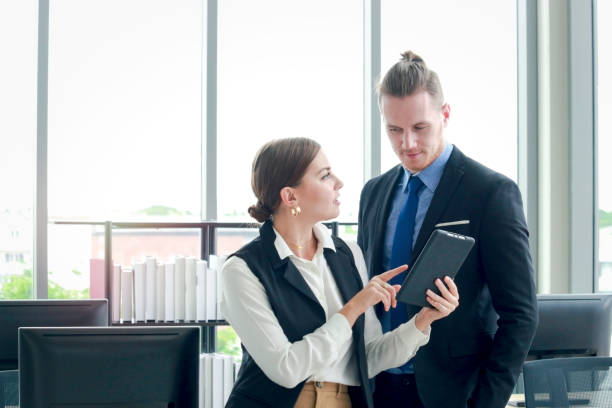 istock Young smart businessman and businesswoman using digital tablet together, discussion about work in the office 1212359655