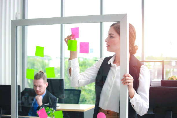 istock Young beautiful successful business woman writing her idea on post-It sticky note paper, working in office, critical thinking in project work 1212360525