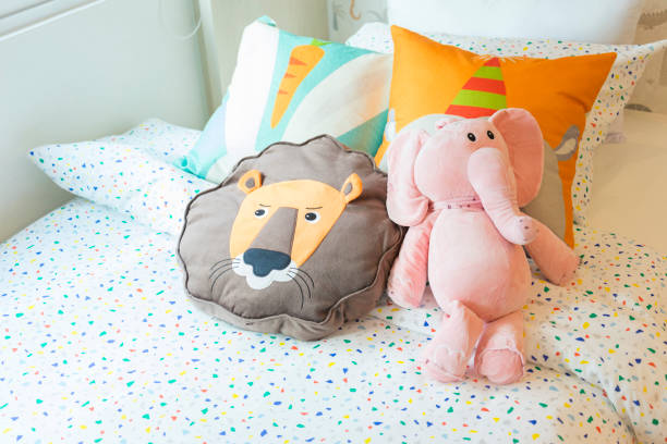 Cute plush doll on warm bed in children bedroom.