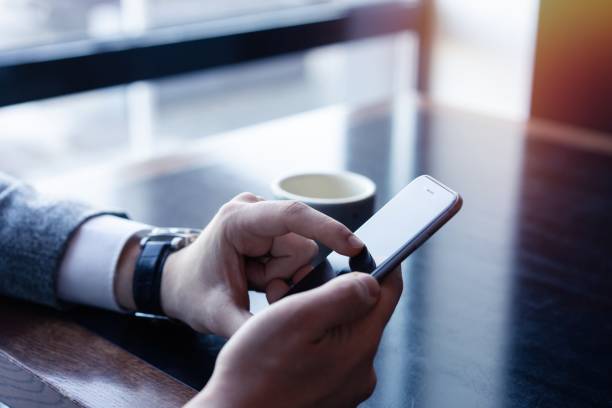 istock Business man holding smartphone, using application to booking suite in hotel for business trip, using wireless connection to internet, resting in cafe, drinking coffee. 1212368024