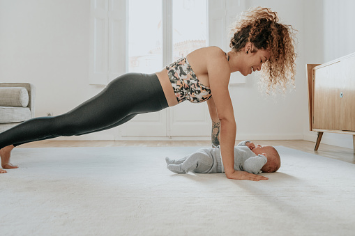 Woman exercising at home with baby