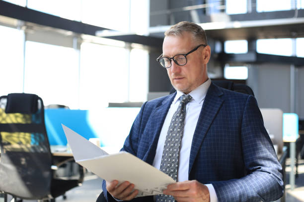 istock Successful mature entrepreneur is studying documents with attentive and concentrated look. 1212371534