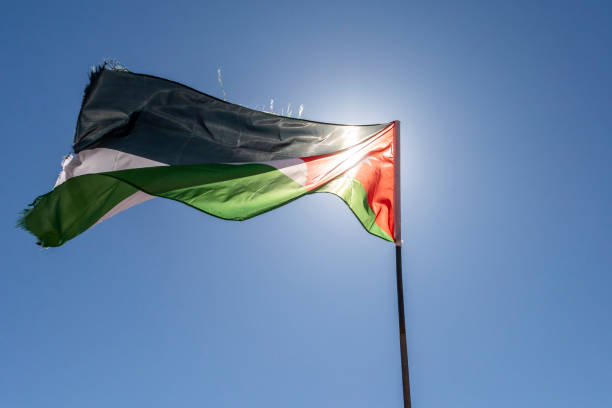 istock Waving flag of Jordan against clear blue sky and sun. 1212373855