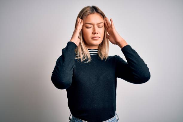 istock Young beautiful blonde woman with blue eyes standing over white isolated background suffering from headache desperate and stressed because pain and migraine. Hands on head. 1212374879