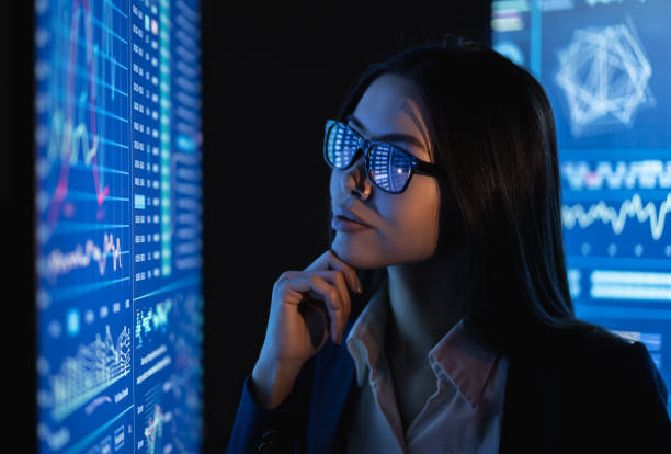 istock The business woman looks on a large blue screen with chart 1212374978