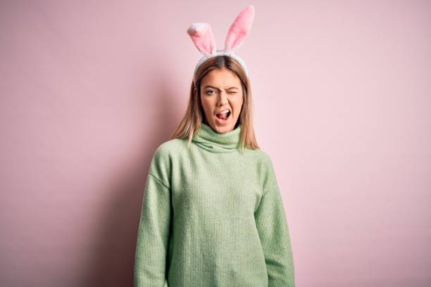 istock Young beautiful woman wearing easter rabbit ears standing over isolated pink background winking looking at the camera with sexy expression, cheerful and happy face. 1212376217