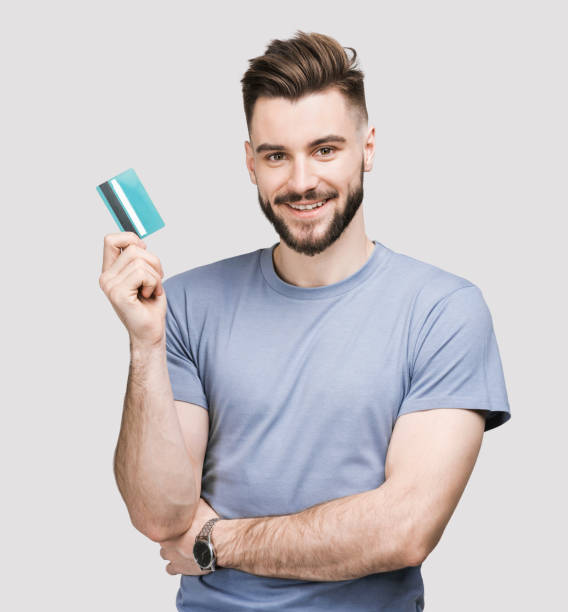 jovem alegre mostrando cartão de crédito - showing buying paying clipping path - fotografias e filmes do acervo