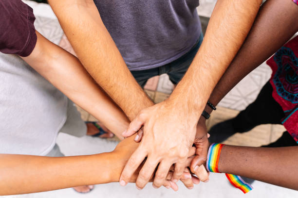 Hands of a group of people of different ethnicities with an lgtb flag bracelet Hands together of a group of people of different ethnicities with an lgtb flag bracelet in the street allegory painting photos stock pictures, royalty-free photos & images