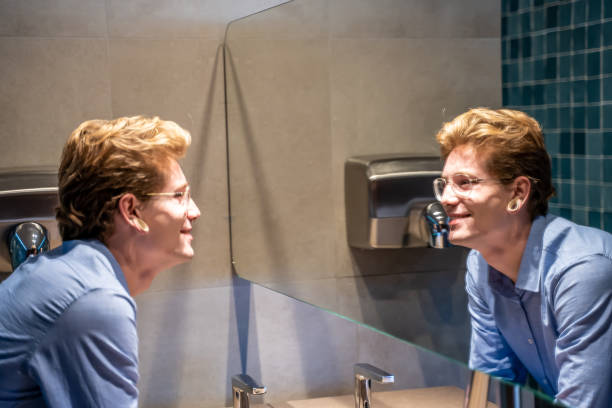 istock Young man in front of a bathroom mirror looking at his reflection in the mirror 1212376894