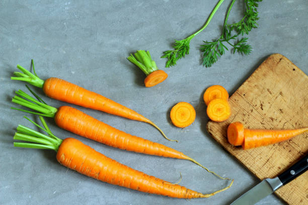 istock Carrots, knife and wooden board on grey concrete background. 1212376987