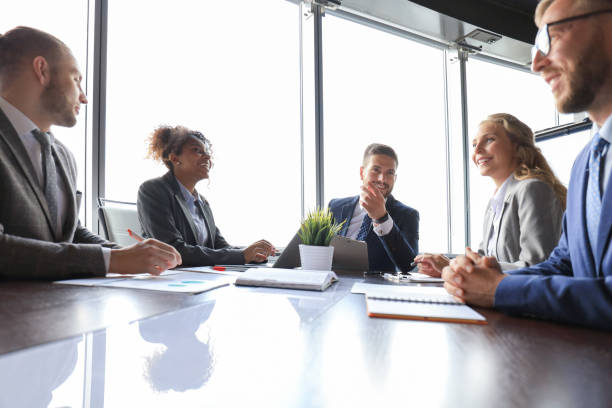 istock Group of young modern people in formalwear smiling and discussing something while working in the modern office 1212377090