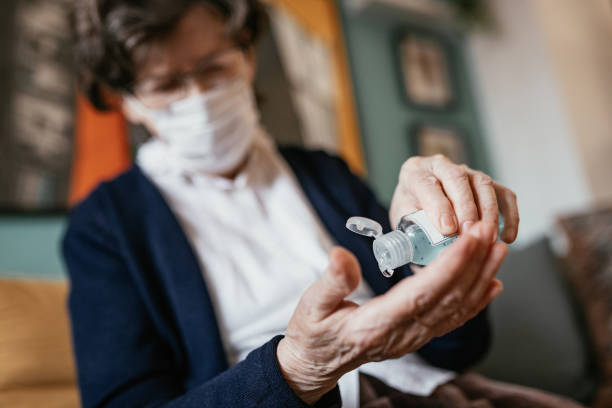 mujer mayor que aplica desinfectante de manos en casa - hand sanitizer liquid soap hygiene healthy lifestyle fotografías e imágenes de stock