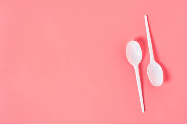 istock Two white disposable spoons on pink background. Concept of save environment, ecology, recreation on picnic, party and other events. Copy space. Top view 1212380409