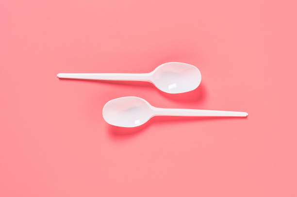 istock Two white disposable spoons on pink background. Concept of save environment, ecology, recreation on picnic, party and other events. Top view 1212380412