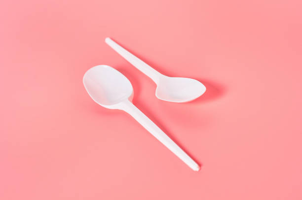 istock Two white disposable spoons on pink background. Concept of save environment, ecology, recreation on picnic, party and other events 1212380413