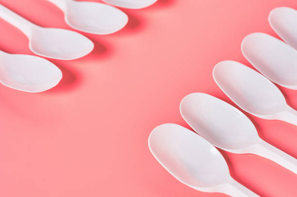 istock Rows of white disposable spoons scattered on pink background. Concept of save environment, ecology, recreation on picnic, party and other events. Copy space 1212380427