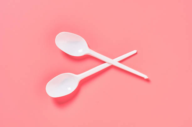 istock Two white disposable spoons scattered on pink background. Concept of save environment, ecology, recreation on picnic, party and other events. Top view 1212380428