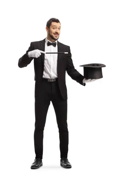 Full length portrait of a magician with a magic wand and hat isolated on white background