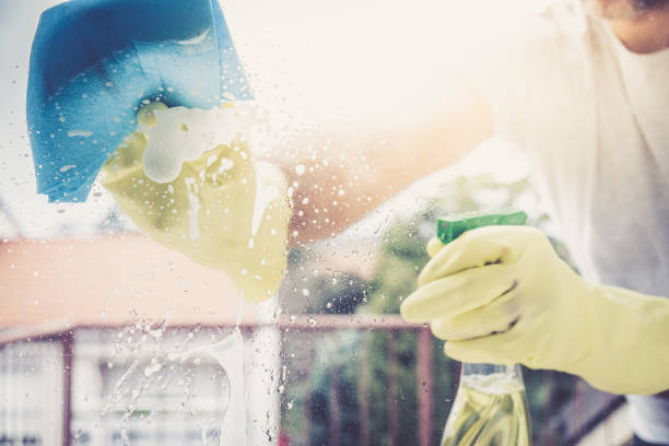 istock COVID-19 wiping down surfaces, Cleaning Wipe and Hands Close Up, Through Window View 1212382213