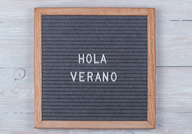 istock grey felt Board with text in Spanish Hello summer . top view on a wooden background 1212382900