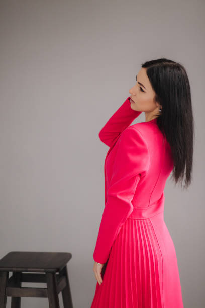 istock Attractive brunette model in crimson dress on gray background in studio 1212383322