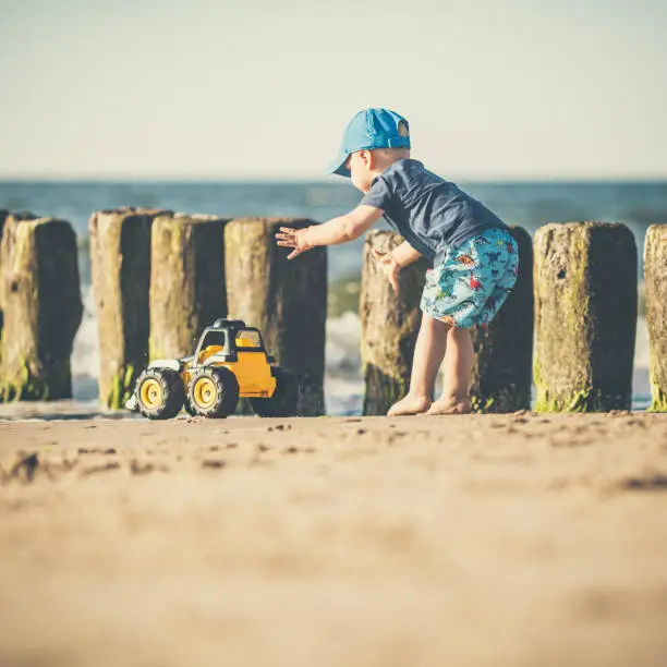 Toddler boy playing with toys on a sunny beach. Little child walking on sand. Beautiful inspirational beach and ocean view, landscape.