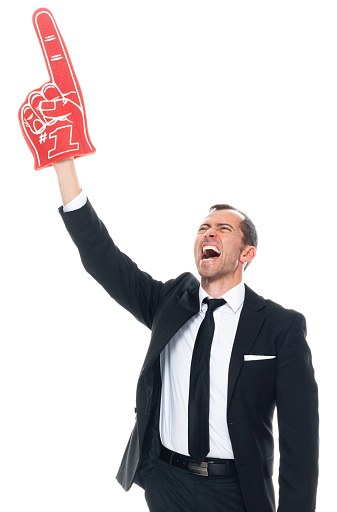 Portrait of aged 40-44 years old with brown hair caucasian male fan - enthusiast standing in front of white background wearing businesswear who is laughing and cheering who is showing with hand and holding foam hand